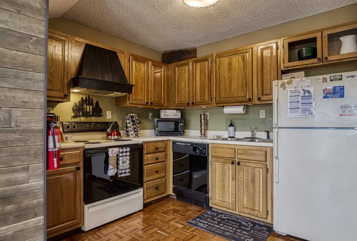 A welcoming kitchen with wood cabinetry, a modern stove, a full refrigerator, and a spacious countertop. The setting feels cozy, emphasizing functionality and warmth. There is ample space for cooking and meal prep, and the inviting atmosphere suggests a place where memories are made over shared meals.